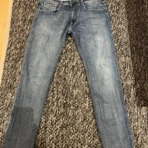 Replay Anbass slim fit jeans blå - Snygga blå Replay Anbass jeans i slim fit som är limited edition med den gröna Patchen med suede tyg.  Jeansen har en lätt tvättad look och är tillverkade i mjukt denimtyg. Perfekta för dig som gillar en smalare passform och stilren design. Även sparsamt använda. Passar 32-34 i midjan och någon som är mellan 175-185. Nypris 1950kr!