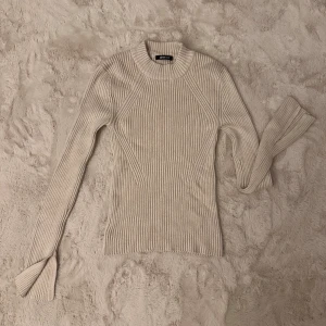 Beige ribbad tröja - Gina Tricot - Supersnygg beige ribbad tröja från Gina Tricot med ribbad struktur och figurnära passform. Tröjan har långa ärmar och en högre rund halsringning.