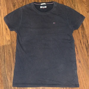 Mörkblå t-shirt från Tommy Hilfiger - En stilren mörkblå t-shirt från Tommy Hilfiger med klassisk passform och liten broderad logga på bröstet. Perfekt basic-plagg med rund hals och korta ärmar. Tillverkad i mjuk bomull för skön känsla hela dagen.
