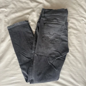 Grå skinny taper jeans från 7 For All Mankind - Snygga grå jeans från 7 For All Mankind i modellen skinny taper. Jeansen har klassisk femficksdesign, smal passform och är tillverkade i mjukt jeansmaterial. Perfekt för dig som gillar en modern och stilren look.