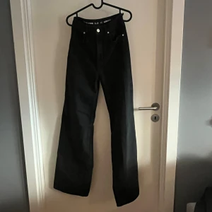 Svarta Tower Wide jeans, storlek 26 - Säljer ett par svarta jeans från Tower Wide i storlek 26 och längd 32. Modellen har hög midja och breda, raka ben.  Klassisk femficksdesign med silverfärgade knappar och dragkedja. 