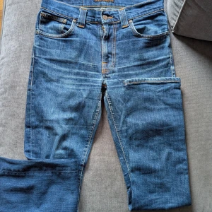 Nudie jeans Grim Tim 29/32 - Sjukt ovanliga Nudie jeans pre-massproduced. Gjorda mellan 2001-2006 vilket man ser genom att det bara står "Nudie" på baksidan istället för NudieJeans, samt nudies klassiska sömmar. Sjukt bra skick för sin ålder, ända är små hål i skrevet men lagas gratis och snyggt i nudies repair shop. Storlek 29/32