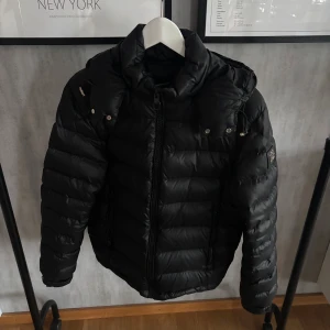 Svart pufferjacka med huva bvaldi  - Säljer en svart pufferjacka med huva och dragkedja framtill. Jackan har quiltad design, två sidofickor med dragkedja och justerbar dragsko vid huvan. Perfekt för kalla dagar och riktigt skön att bära.