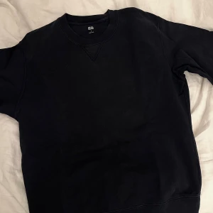 Mörkblå sweatshirt från Uniqlo, stl S - En klassisk mörkblå sweatshirt från Uniqlo i storlek S. Tröjan har rund halsringning, ribbade muddar och är tillverkad i mjuk bomull. Perfekt basic att ha i garderoben och funkar året runt.