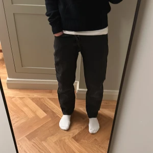 Svarta relaxed jeans från Jack & Jones - Svarta jeans från Jack & Jones, modell Relaxed/Chris. De har en avslappnad passform med raka ben och klassisk femficksdesign. Jeansen är tillverkade i jeansmaterial och har midwaist. Perfekt för dig som gillar en loose och chill stil.