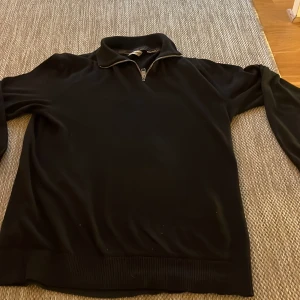 Svart half zip tröja Jack & Jones - Svart långärmad tröja från Jack & Jones med krage och half zip-dragkedja framtill. Tröjan har en clean look med ribbade muddar vid ärmslut och nederkant. Perfekt för dig som gillar stilrena och enkla plagg.