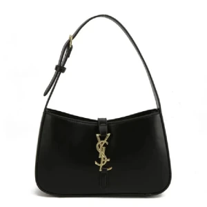 Svart axelväska från YSL i skinn - Snygg svart axelväska från YSL i slätt skinn med justerbart axelband och ikoniskt guldigt YSL-logo framtill. Väskan har dragkedja upptill och stilren, avlång form som ger en lyxig vibe. Perfekt för dig som vill ha en klassisk och trendig accessoar.