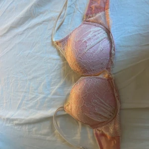 Söt Bh med spets och små stenar - Söt rosa bh från H&M med vadderade kupor, täckt av blommig spets och små stenar/diamanter. Axelbanden är tunna och justerbara, och det finns en liten rosett mellan kuporna. 