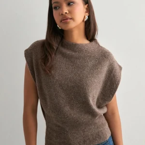NELLY Half Polo Knit Vest - Säljer en brun stickad topp med mjuk och lite fluffig känsla. Modellen är ärmlös med breda axlar och har en avslappnad passform som sitter snyggt vid midjan. Slutsåld överallt💕