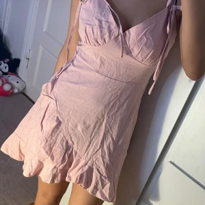 Rosa klänning - Söt ljusrosa klänning med volangkant och knytband på axlarna. Ger en romantisk, feminin look 💕 Lätt tyg – perfekt för sommar, dejt eller vardag! Fint skick ✨aldrig använd  💬 Pris kan diskuteras!  🌸 En gullig och trendig klänning som passar till alla tillfällen!