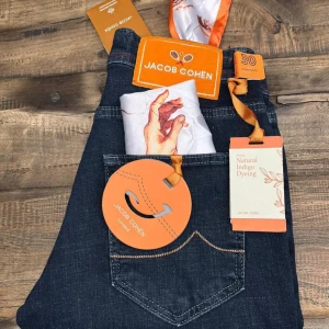 Jacob Cohën jeans (nya) - Jacob Cohën Nick Slim jeans i mörkblå tvätt med orange detaljer och kontrastsömmar. Slim passform, klassisk femficksmodell och exklusiv finish. Tillverkade i högkvalitativt jeansmaterial med naturlig indigo-färgning. Snyggt broderad logga och unika etiketter. Ny pris runt 5500, hör av dig vid minsta fråga 🙌