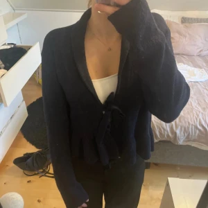 Mörkblå stickad kofta från Nelly - Mysig mörkblå stickad kofta från Nelly med knytband framtill och lätt utsvängd nederdel. Koftan har lång ärm och en snygg krage som ger en chill men ändå stilren look.  Säljer då den inte kommer till användning 💗