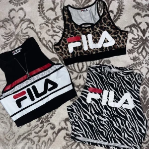 Tre sportiga crop tops från FILA - Tre snygga crop tops från FILA: en med leopardmönster, en svartvit med zebramönster och en svartvit med röda detaljer och dragkedja framtill. Alla har stor FILA-logga framtill och är perfekta för träning eller streetstyle. Säljes i kit alla 3. Önskar du köpa styck så skicka ett meddelande.  Strl s-m