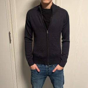 Mörkgrå stickad kofta  - Mörkgrå stickad kofta från Harvest med hel dragkedja framtill, Storlek xs/s Nypris 599kr säljs för 289kr. Skick 8/10 eftersom det var ett litet hål på baksidan av kragen men det är sytt. Det syns på sista bilden! Passar ungefär personer som är 165-175.