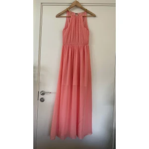 Ljusrosa långklänning med plisserad topp - Superfin ljusrosa långklänning med plisserad överdel och markerad midja. Klänningen är ärmlös och har en flowy kjol i tunt, lätt material som ger en luftig känsla. Perfekt för sommarens alla tillfällen när du vill känna dig extra fin. Helt NY. 