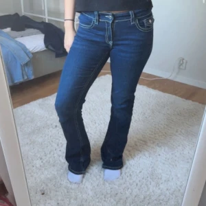 Blå bootcut jeans från Gina Tricot - Mörkblå jeans från Gina Tricot med bootcut-modell och kontrastsömmar. Klassiska femficksdetaljer och snygga ficklock bak med knapp. Jeansen har låg midja och passar perfekt nu till hösten💗