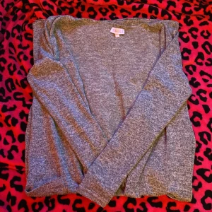 Grå kofta från Skill med fickor - Mysig gråmelerad kofta från Skill i storlek 146/152. Koftan har lång ärm, två praktiska fickor framtill och en enkel, öppen design utan knappar. Perfekt för lager-på-lager och chill dagar. Materialet känns mjukt och skönt mot huden.