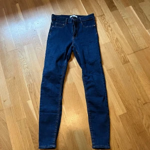 Mörkblå Molly skinny jeans M - Säljer ett par mörkblå Molly jeans från Gina Tricot i storlek M. Modellen är skinny med smal passform och klassisk femficksdesign. Jeansen har hög midja och är tillverkade i stretchigt denim för en bekväm känsla. Perfekt för dig som gillar tajta jeans!