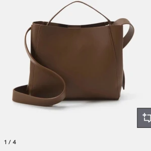 Brun axelväska i skinn - Snygg brun axelväska i stilren design med både axelrem och handtag. Väskan är tillverkad i slätt skinn och har en enkel, boxig form som passar till många outfits. Perfekt storlek för att få plats med det viktigaste och lite till.