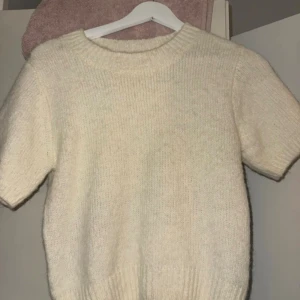 Stickad vit tröja från Gina Tricot - Mysig stickad tröja från Gina Tricot i storlek S. Tröjan är vit med korta ärmar och har en rund halsringning med ribbad kant. Perfekt för dig som gillar enkel och clean stil med en soft känsla. Den är i nyskick!