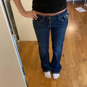 Mörkblå bootcut jeans med knappfickor - Snygga mörkblå jeans med bootcut passform och låg midja. 