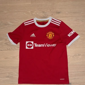 2021/22 Manchester United Adidas matchtröja Ronaldo  - Röd Manchester United fotbollströja från Adidas med klubbmärke på bröstet, vita detaljer och tryck från TeamViewer och Kohler. Klassisk rund halsringning och tre vita ränder på axlarna. Pris går givetvis att diskuteras även så med någon annan fråga:)