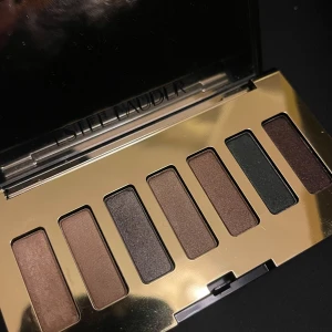 Estée Lauder Pure Color Envy ögonskuggspalett - Snygg ögonskuggspalett från Estée Lauder med sju nyanser i brunt, guld, grönt och mörklila. Paletten har en lyxig guldfärgad förpackning med spegel. Perfekt för att skapa både naturliga och mer dramatiska ögonlooks.
