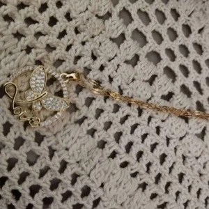 Snygg  halsband med fjäril och text i rostfritt stål med zirkon - Unikt halsband i rostfritt stål med en rund berlock dekorerad med glittriga stenar, en fjäril och texten 'Love' i snygg skrivstil. Kedjan är länkad och har en modern känsla. Perfekt för dig som gillar detaljer och bling.