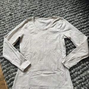 Ljusbeige långärmad tröja Bondelid - En basic ljusbeige långärmad tröja från Bondelid. Tröjan har rund halsringning och är tillverkad i mjuk bomull, perfekt att styla med jeans eller kjol. Enkel och clean design som funkar till många olika looks.