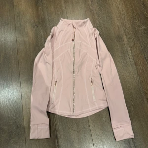 Lululemon define jacket xxs/xs - Snygg ljusrosa jacka i sportig stil med hel dragkedja framtill och två fickor med dragkedja. Jackan är figursydd och har långa ärmar med extra breda muddar. Tillverkad i ett stretchigt material av 80% nylon och 20% elastan. xxs / xs
