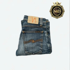 Nudie Jeans - Snygga blå jeans från Nudie Jeans med klassisk femficksdesign och orangea sömmar på bakfickorna. Jeansen har en rak passform och är tillverkade i slitstarkt bomullstyg. Perfekta för dig som gillar en tidlös och avslappnad stil. Byxorna är i mycket bra skick, skriv vid frågor eller mer bilder⚜️
