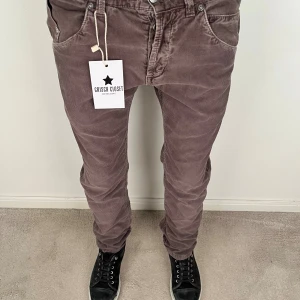 Bruna manchesterbyxor dondup - Snygga bruna manchesterbyxor från dondupmed klassisk femficksdesign och coolt broderad logga på bakfickan. Byxorna har normal passform och raka ben, perfekt för dig som gillar retrovibbar och mjukt material.