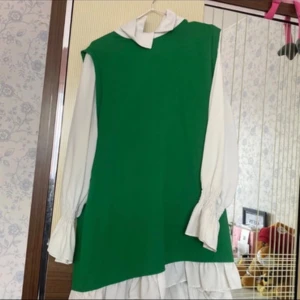 Grön och vit klänning från Lalstore - Supersöt klänning från Lalstore i starkt grön med vita detaljer. Klänningen har långa, puffiga ärmar med smock vid handlederna och en vit krage. Den är rak i modellen och har volang nertill. Perfekt för dig som vill sticka ut med färg och stil.