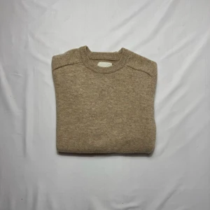 Tröja A Day's March - Beige stickad tröja från A Day's March i mjuk ullmix i storlek M. Klassisk rund halsringning och ribbade muddar vid ärmslut och nederkant. Perfekt för lager-på-lager och chill höst- och vinterstil.                                                                            Tveka inte att höra av dig vid minsta fundering!