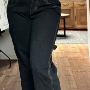 Svarta cargopants med kontrastsömmar - Säljer mina svarta cargopants med snygga kontrastsömmar då jag nu mera är M ibyxor och tycker därför de inte sitter lika bra på mig som när jag var i stl S . Byxorna har låg midja och en loose/rak passform. 