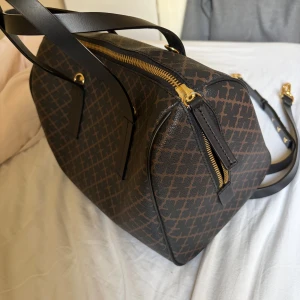 Handväska By Malene Birger - Snygg handväska från By Malene Birger i brunt och svart med ikoniskt grafiskt mönster.Väskan är i fint skick knappt använd. Väskan finns inte att köpa ny. Alla tryckta stämplar/ loggor är intakta och inget slitage, se bild. Original axelband förnöjer med, samt original innefickan som är avtagbar. De finns små skrapmärken undertill som knappt syns i verkligheten, se bild. Även en liten fläck i, inget som direkt syns heller se bild.  Vid frågor, tveka inte på att skriv🩷