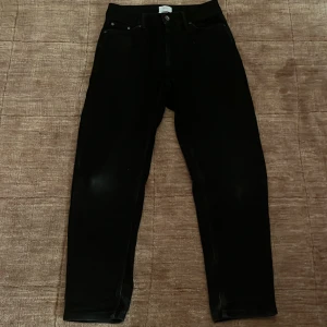 Svarta jeans från Grunt Organic - Snygga svarta jeans från Grunt Organic med klassisk femficksdesign och raka ben. Jeansen har en knapp med logga och är tillverkade i ekologisk bomull. Passar dig som gillar stilrena och enkla svarta jeans med normal passform.