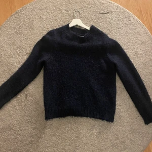 Mörkblå stickad tröja från Stories - Knappt använd. 