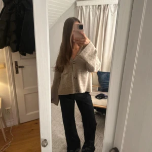 Svarta bootcut byxor låg midja - Säljer ett par svarta bootcut byxor med medelhög midja. Byxorna har en klassisk rak passform upptill och blir vidare nedtill, vilket ger en snygg siluett. Materialet är mjukt och följsamt, perfekt för dig som gillar en trendig och avslappnad look.