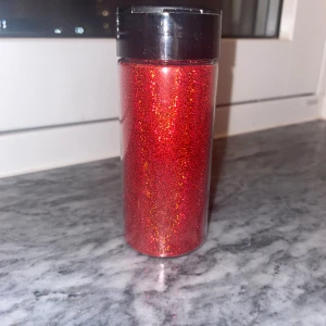 Rött lösglitter för dekoration - Säljer ett stort rör med superfint rött glitter som passar perfekt till kreativa dekorationer,inslagningar eller detaljer. Glittret är intensivt rött med skimrande effekt och kommer i en genomskinlig plastburk med svart lock. Perfekt för dig som vill sticka ut med din makeup.