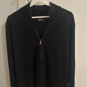 Mörkblå fullzip från Oscar Jacobson - Mörkblå fullzip tröja från Oscar Jacobson i merinoull. Bekväm och nästan aldrig använd i storlek L. Nypris 1800kr