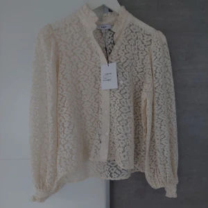 Vit spetsblus från Suncoo - Romantisk vit spetsblus från Suncoo med volangkrage och knappar framtill. Blusen har långärmade puffärmar med resår vid ärmslut och är helt täckt av ett vackert spetsmönster. Perfekt för dig som gillar en feminin och trendig look. Ny ä, Ny pris 1299kr passar en S/M endast 450kr  finns på mer ställen allt jag har, tar bort om direkt om den säljs på annan sida. 