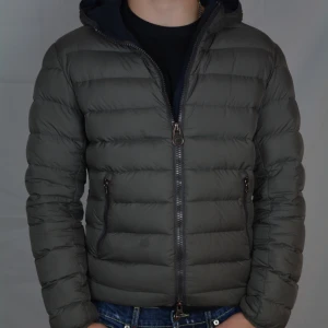 Colmar Jacka - Riktigt fet grå dunjacka med luva från Colmar. Jackan är i bra skick men har en liten fläck på magen och axeln. Jackan är i storlek M, men passar även S.                                                          Vid frågor eller funderingar är det bara att höra av sig, och kom ihåg, alltid 14 dagars ångerrätt hos oss på Revalo!