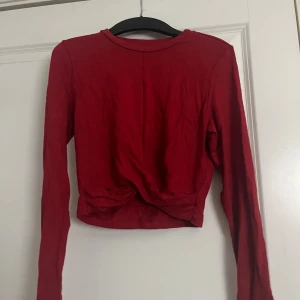 Röd croppad långärmad topp Gina Tricot - Säljer en röd croppad långärmad topp från Gina Tricot i storlek S. Toppen har en twistad detalj framtill och är tillverkad i mjuk bomull. Finns en fläck på framsidan men eftersom den är twistad syns det knappt. 