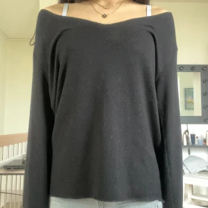 Svart offshoulder stickad tröja - Svart stickad tröja med offshoulder och lång ärm. Tröjan har en mjuk och lite lös passform, perfekt för dig som gillar en chill och enkel stil. Materialet är stickat och känns skönt mot huden. Passar dig som vill ha en basic men snygg topp till jeans eller kjol.