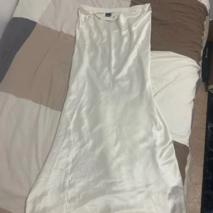 Vit långklänning i satin från Gina Tricot - Supersnygg vit maxikjol från Gina Tricot i glansigt satinliknande material. Perfekt för dig som vill ha en stilren och elegant look. Använd 1 gång då den var för stor 