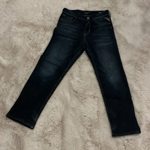 Mörkblå jeans från Replay, strl 10A - Snygga mörkblå jeans från Replay med klassisk femficksdesign och coola kontrastsömmar på bakfickan. Modellen har rak passform och är tillverkad i slitstarkt denimtyg. Perfekt för dig som gillar stilrena och tidlösa jeans.