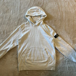 Vit hoodie från Stone Island - Säljer en stilren vit hoodie från Stone Island som är en lite mer tunnare model. Köpt från Stone Island och är i ett bra skick. Storlek M passar även L. Tröjan stryks innan den skickas.  Och som alltid kan priset diskuteras men vi utgår ifrån 1200 kr