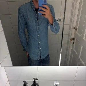 Skjorta Polo Ralph Lauren - Snygg ljusblå jeansskjorta från Polo Ralph Lauren i slim fit-modell. Skjortan har klassisk krage med knappar, lång ärm och ikonisk broderad logga på bröstet.