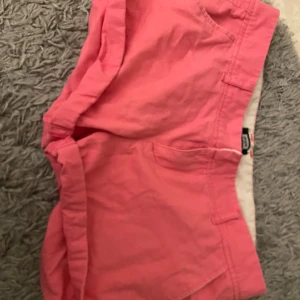 Rosa shorts från Bik Bok, storlek M - Snygga rosa shorts från Bik Bok i storlek M. Modellen har klassisk femficksdesign med två bakfickor med knapp och framfickor. Tillverkade i mjuk bomull med lowaist passform, perfekta för varma dagar. Fräscha och trendiga färgen gör dem till ett måste i garderoben.